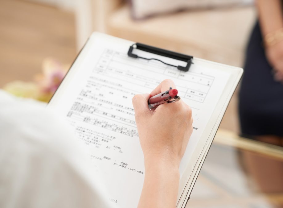 クリップボードに記入する施術者